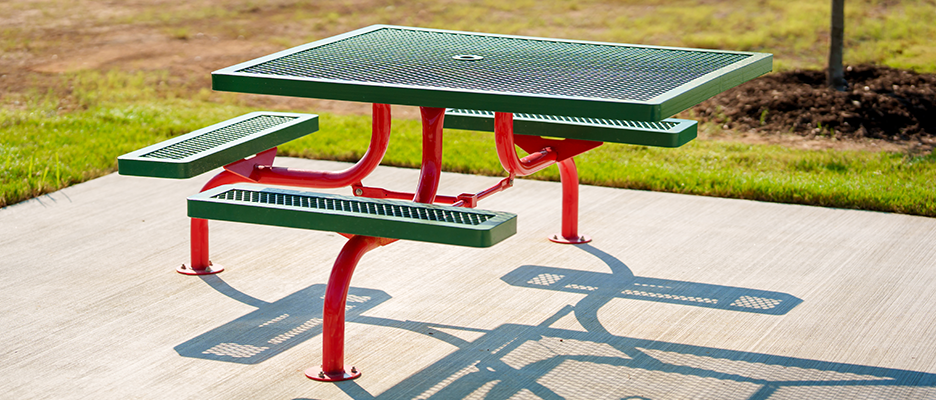 Single pedestal picnic table with center-mounted frame and perforated metal seating for easy access and cleaning